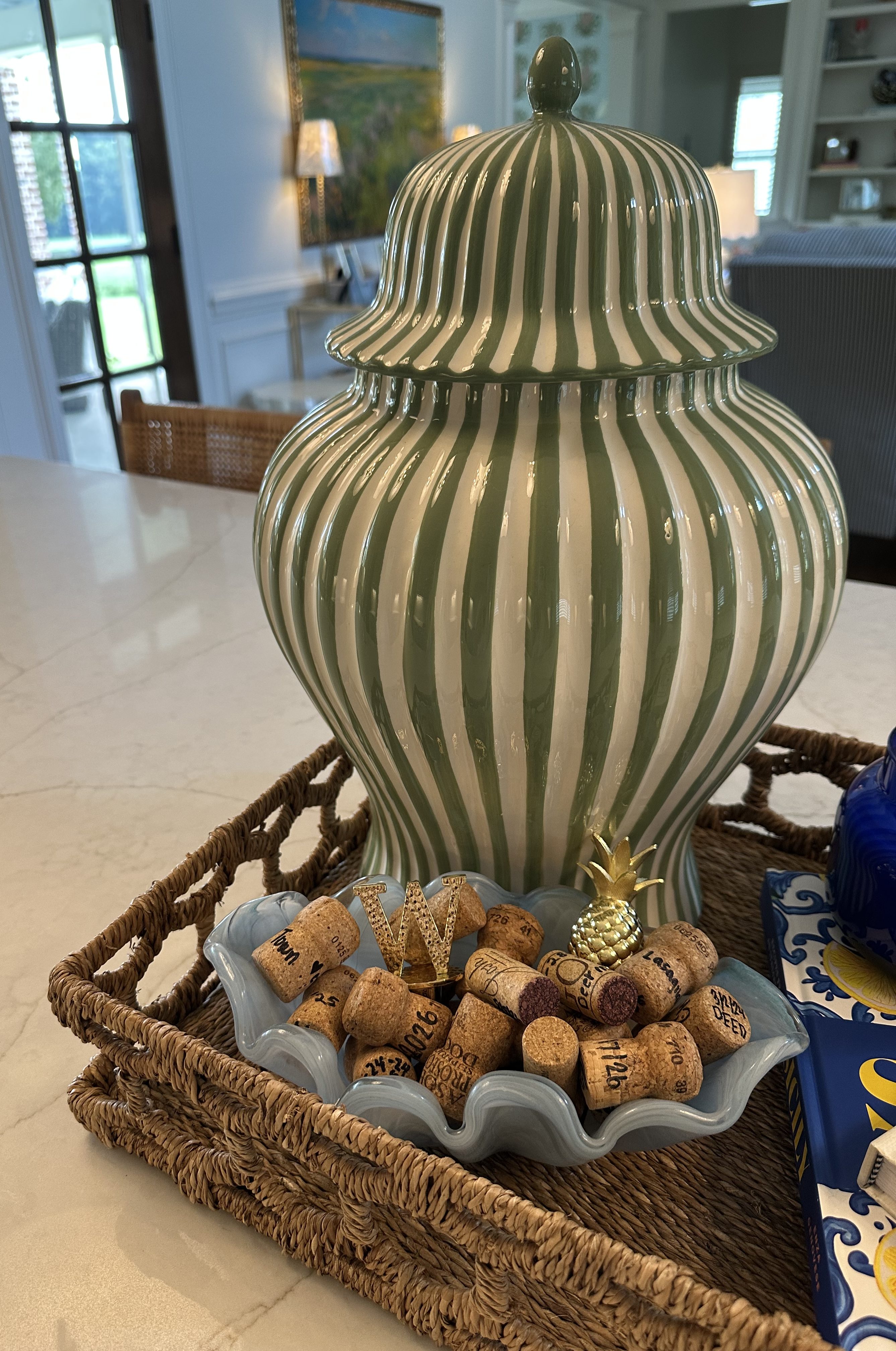 Kitchen island decor with a green striped vase, stacked cookbooks and candle on a woven tray