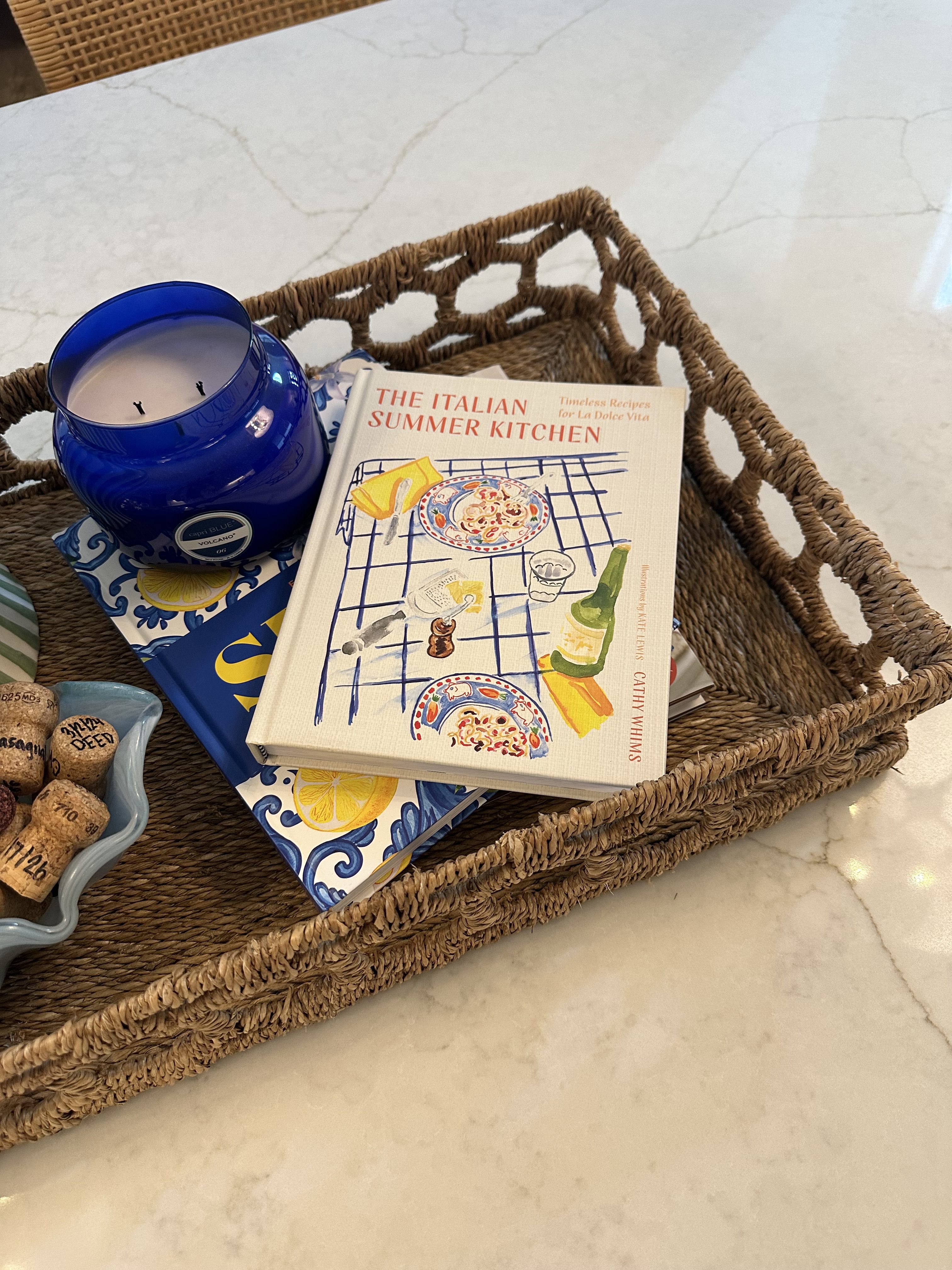 Styled kitchen island with colorful cookbooks, green vase, candle and keepsake wine corks